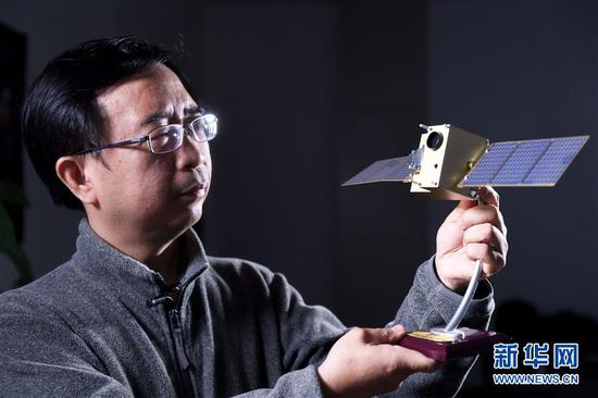 潘建伟在中国科学技术大学的办公室内与“墨子号”量子卫星模型合影(12月13日摄)。 新华社记者 张端 摄