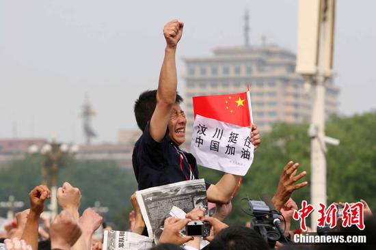 2008年5月19日,北京天安门广场上的民众为地震遇难者默哀,一位来自四川的男子高举右手为家乡加油。中新社记者 富田 摄