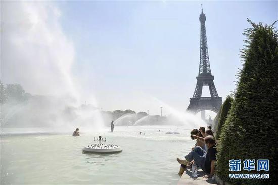 ▲7月27日，人们在法国巴黎埃菲尔铁塔附近的喷泉中避暑。（图片来源：新华