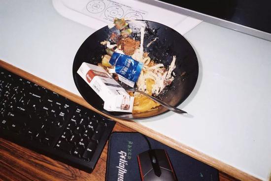 ▲网吧桌面随处可见的餐盘，而所有能够盛放物品的器皿都会被用来放烟屁股 | 来源：陈志贤《INTERNET CAFE! PANDA》 