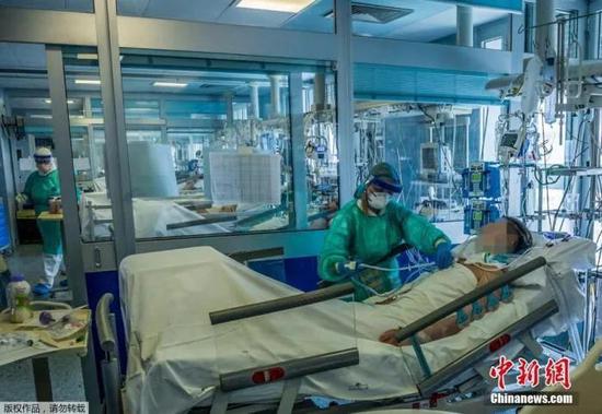 当地时间3月23日,意大利米兰东南部的克雷莫纳医院重症监护室,医护人员正在为感染新冠状肺炎的重症患者治疗。