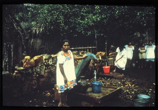 在这幅1993年的照片中，这名玛雅妇女正从一只集中式龙头中取水，这只龙头由一部气动水泵驱动，和从水井里提水相比，每天能为她节省约400千卡热量。| karen Kramer