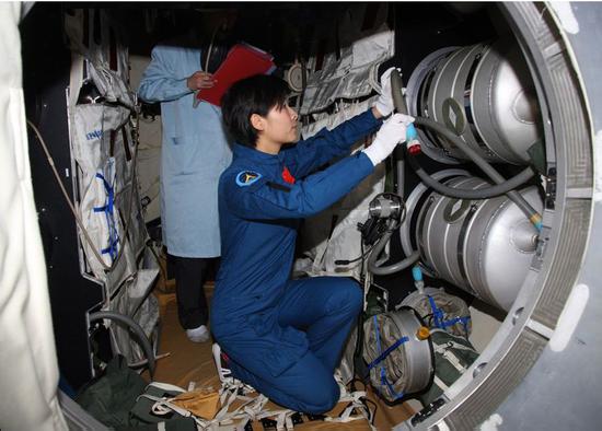 刘洋在天宫一号组合体模拟舱内检查实验设备(图片来源:http://www.91esh.com/)