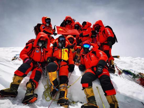 2020年5月27日，测量登山队员在珠峰峰顶与国旗合影。国测一大队供图