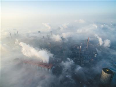 2016年12月22日,邯郸,钢铁厂烟囱穿过晨雾。 新京报记者 王子诚 摄