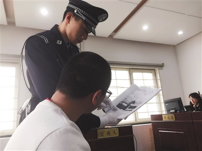 微信一分钱充10元话费 法警为被告人王某出示证据。昨日上午,被控涉嫌破坏计算机信息系统罪的王某在法院受审。新京报记者 刘洋 摄