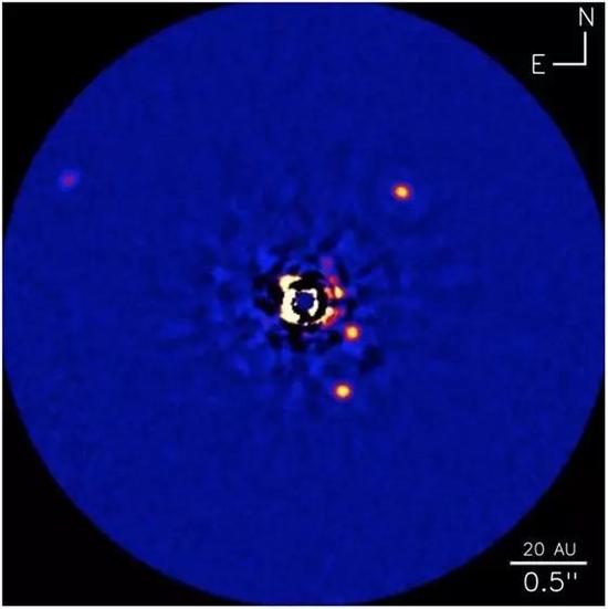 图1. 亮星HR 8799和它已知的四颗巨型行星的图像。四颗行星分别为恒星右侧、上方和下方的亮点、以及左上角的那个较暗的点。恒星其实比行星亮很多很多，但这张图里恒星的光芒被一个恰当放置于恒星前方的遮盖物挡住了。因为这种遮挡并不是完美的，在图片中心可以看到残余的星光从遮盖物边缘透出。HR 8799以及它的四颗比木星还重的行星距离地球约130光年。（加拿大国家研究院、C. 马鲁瓦、凯克天文台）（AU=天文单位）