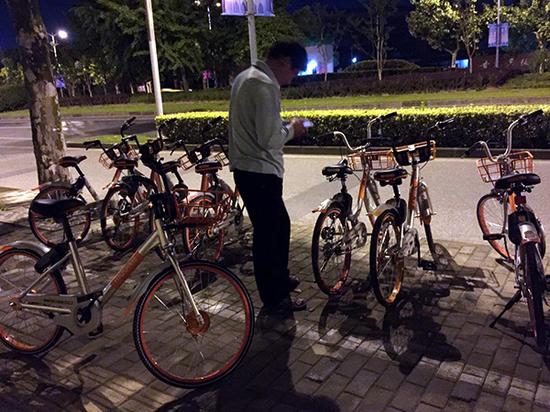 已经骑着一辆单车的中年男子，正在寻找另一辆“红包车”。