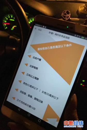 小李拿手机展示滴滴平台的网约车司机标准 中新经纬 吴一尘 摄