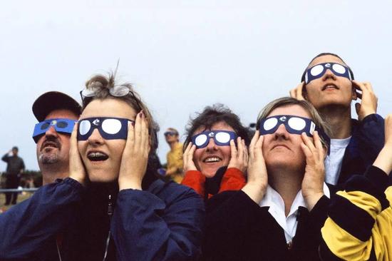 ▲ 1999 年 8 月 11 日，法国 Vauville，人们佩戴上安全眼镜聚集起来观察日食。（Michel Lambert / Getty Images）