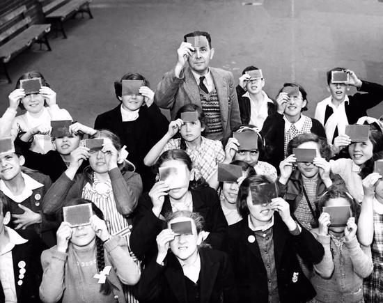 ▲ 1954 年 6 月在伦敦，一名老师在指导他的学生们观看日食。（Hulton Deutsch / Getty Images）