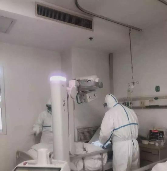 放射科医生穿上防护服，推着移动胸片机，冲向隔离病区的病房里，在病床边为不能动弹的患者拍胸片，图片来源：长江日报
