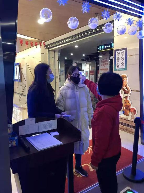 1月23日，通知暂停营业那天，湖北荆州一家华夏国际影城在给员工测量体温（受访者供图）