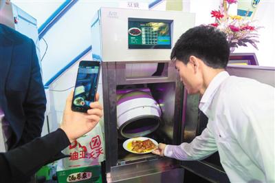 近日,一款商用智能自动炒菜机出现在上交会现场,现场工作人员使用该机器炒制了多款美食,吸引了观众品尝。 王 冈摄(人民图片)