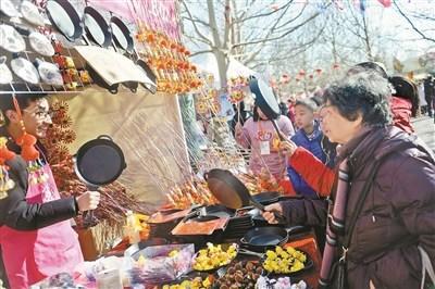 朝阳国际风情节上,不少游客在出售“吃鸡”平底锅的摊位前驻足摄影/本报记者 魏彤
