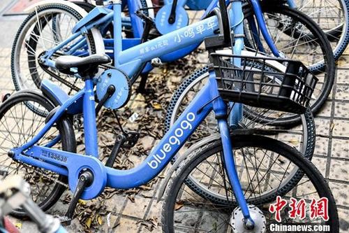 资料图：一辆小蓝单车与其它品牌的共享单车被堆放在路边。中新社记者 陈骥旻 摄