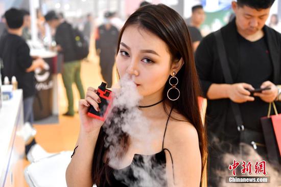 资料图:美女手持电子烟体验。 中新社记者 陈文 摄 研究显示,传统烟草烟雾中有多种已知的致癌物,几乎会