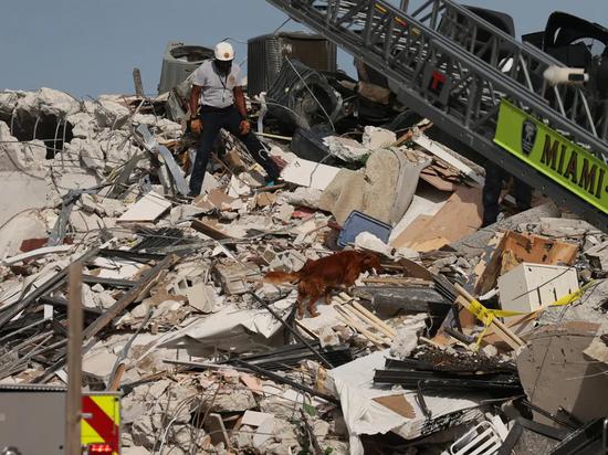 2021 年 6 月 24 日，佛罗里达州瑟夫赛德，一名迈阿密-戴德消防救援官员和一名 K-9 继续在部分倒塌的 12 层尚普兰塔南公寓大楼中进行搜救行动。