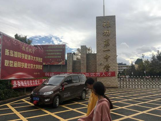 禄劝县第一中学门口,竖立的牌子上是被清华、北大录取的两名同学的名字