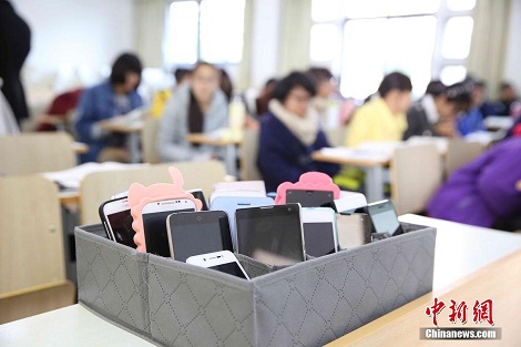 资料图:2014年11月20日,浙江农林大学动物科学专业14级的学生在教室里进行课间休息,他们的手机统一关机并放置在学生会提供的手机框里。 中新社发 陈胜伟 摄 图片来源:CNSPHOTO