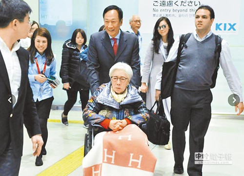 鸿海董事长郭台铭推着坐在轮椅上的母亲，与妻子曾馨莹走出大阪关西国际机场管制区。图自台湾中时电子报