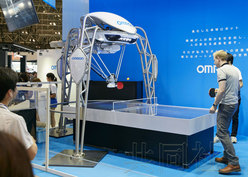 欧姆龙推出世界上首台“乒乓球教练机器人”图为欧姆龙公司开发的能持续与人类进行乒乓球对打的机器人“FORPHEUS”(中)，被吉尼斯世界纪录认定为世界上首台“乒乓球教练机器人”。(共同社)