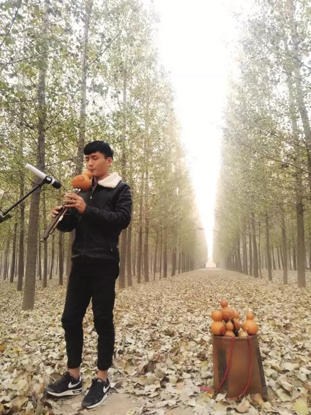 “Mr。亮叔叔”在村旁的杨树林里录制吹葫芦丝视频。