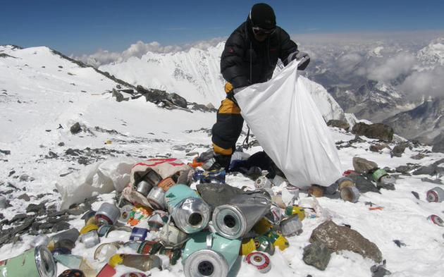 一位夏巴人正在海拔8000米处将垃圾装入袋中。