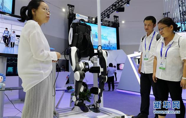 9月17日，工作人员（左）在大会现场向参观者介绍一款外骨骼机器人。新华社记者 方喆 摄