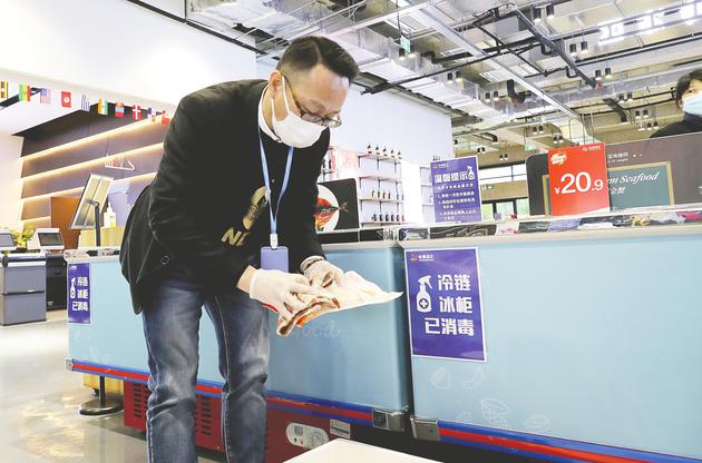 11月26日，上海虹桥品汇健康食品馆工作人员用消毒液擦拭冷冻食品包装 新华社图