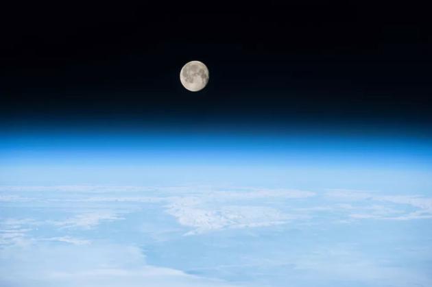 国际空间站拍摄的几近满月状态的明月，悬挂于地球大气之上。