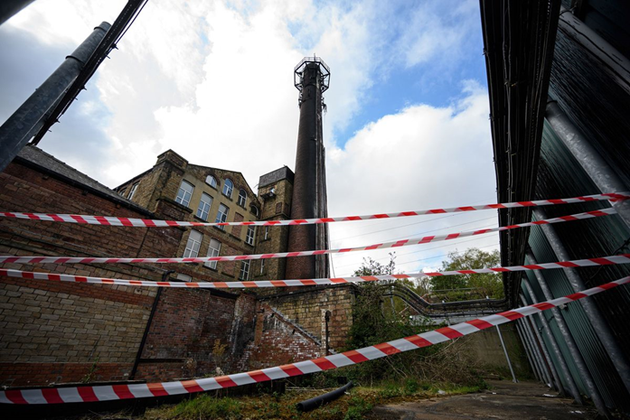 图1：英格兰北部哈德斯菲尔德某处倚靠烟囱的手机信号塔被烧毁，图中是损坏的线缆和电信设备，摄于4月17日