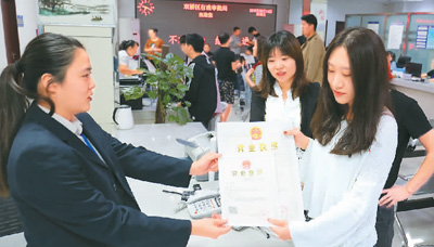 河北省承德市网络代购经营者陈晨从工作人员手中接过带有统一社会信用代码的营业执照。 刘环宇摄