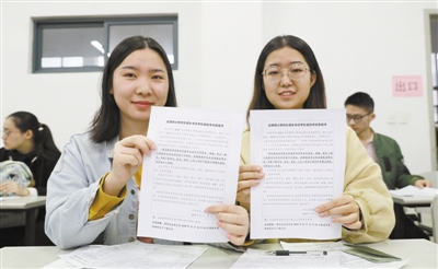 近日,江苏省2019年全国硕士研究生招生考试报名现场,两名考生手持诚信考试承诺书。视觉中国