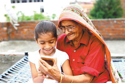 58%的印度农村用户通过互联网观看线上视频，而其中65%—75%是通过手机的4G网络观看。图为在印度的一个村庄，奶奶和孙女一起用智能手机观看视频。 人民视觉