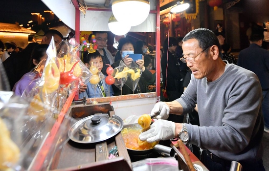 ↑4月29日,在天津古文化街,手工艺人为游客制作糖人。