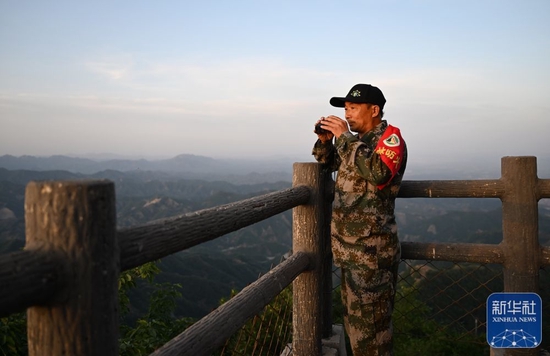 6月1日，朱金保在八仙山聚仙峰峰顶用望远镜远眺观察。