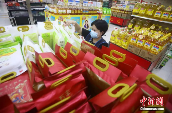 资料图：超市工作人员摆放大米和油等生活必需品。