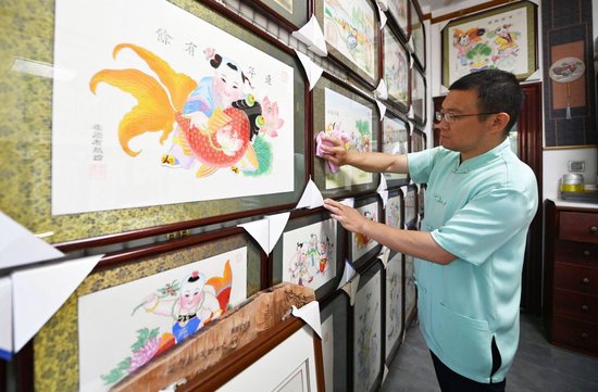 在天津市西青区的杨柳青霍氏古一张画店，霍树林在用布擦拭画框（6月6日摄）。