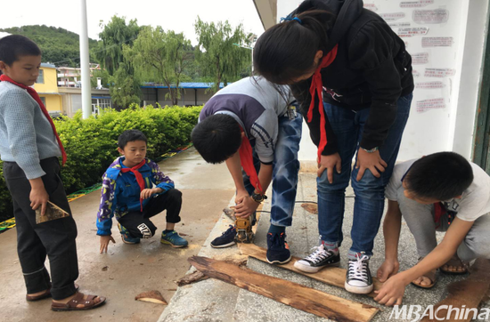 同学们自己动手锯木板做篱笆墙