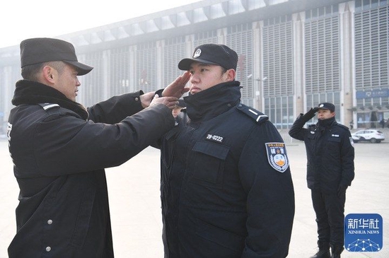 在天津站后广场，李欢（左）在纠正支队辅警的敬礼动作