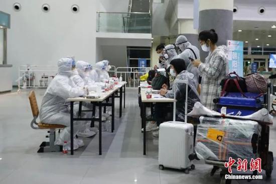 3月23日,位于北京中国国际展览中心新馆的检查入境人员集散点内,旅客在朝阳区咨询台了解集中隔离点情况。