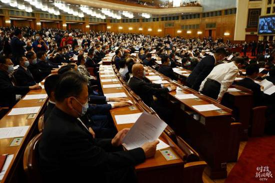 △与会委员认真翻阅政协常委会工作报告。(总台国广记者翟磊拍摄)