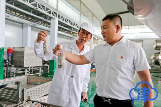 闫志远（右）在车间里检查新一批蔬果深加工产品的外观品质。记者 蒲永河 摄
