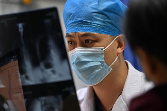 在天津医科大学总医院,晚上坐诊的专家在给患者“看片”(6月2日摄)。