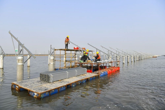 ↑在天津滨海新区龙源海晶盐光互补项目建设现场，建设者在水面上安装光伏板结构组件（2月7日摄）。