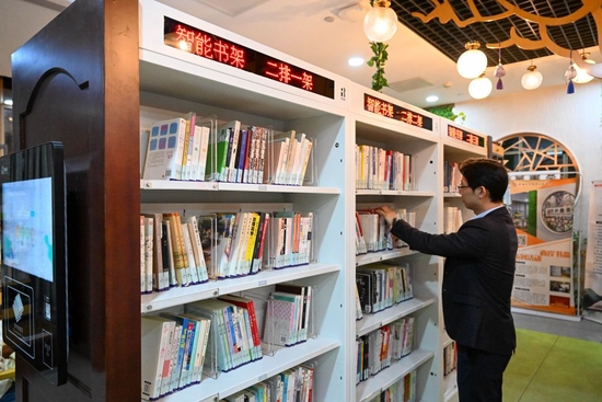 ↑ 在天津市河西区新梅江文体中心西岸书斋，工作人员将图书放置在智能书架上方便读者快速检索（4月19日摄）。