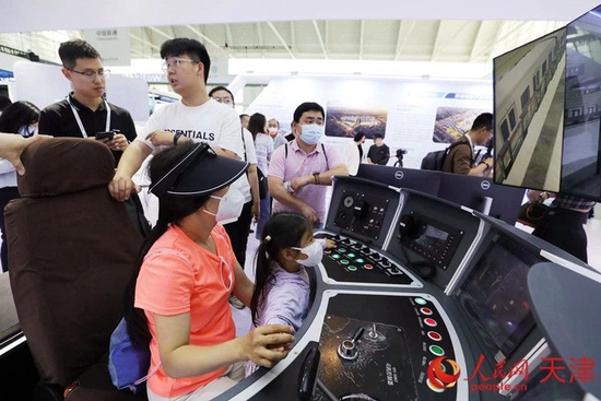一位参观者和孩子在天津轨道交通集团展台体验智能驾驶带来的乐趣。人民网记者 孙翼飞摄