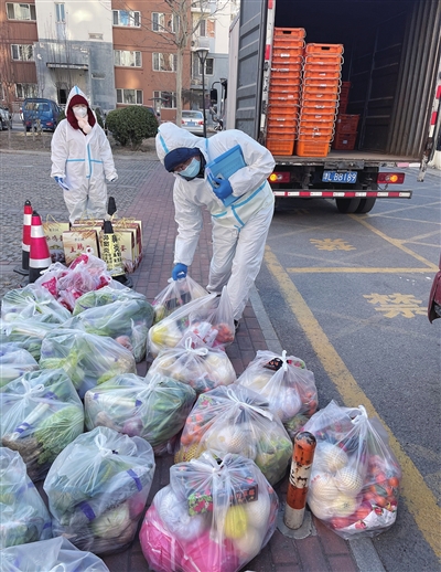 在津南区鑫旺里小区分拣货物后，市商务局机关党员对照订货单把菜送到居民家中。