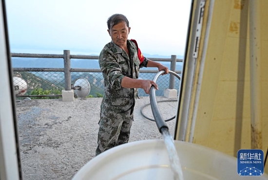 6月1日，朱金保借助通向峰顶的水管管道向森林防火管理站内的水桶内补水。